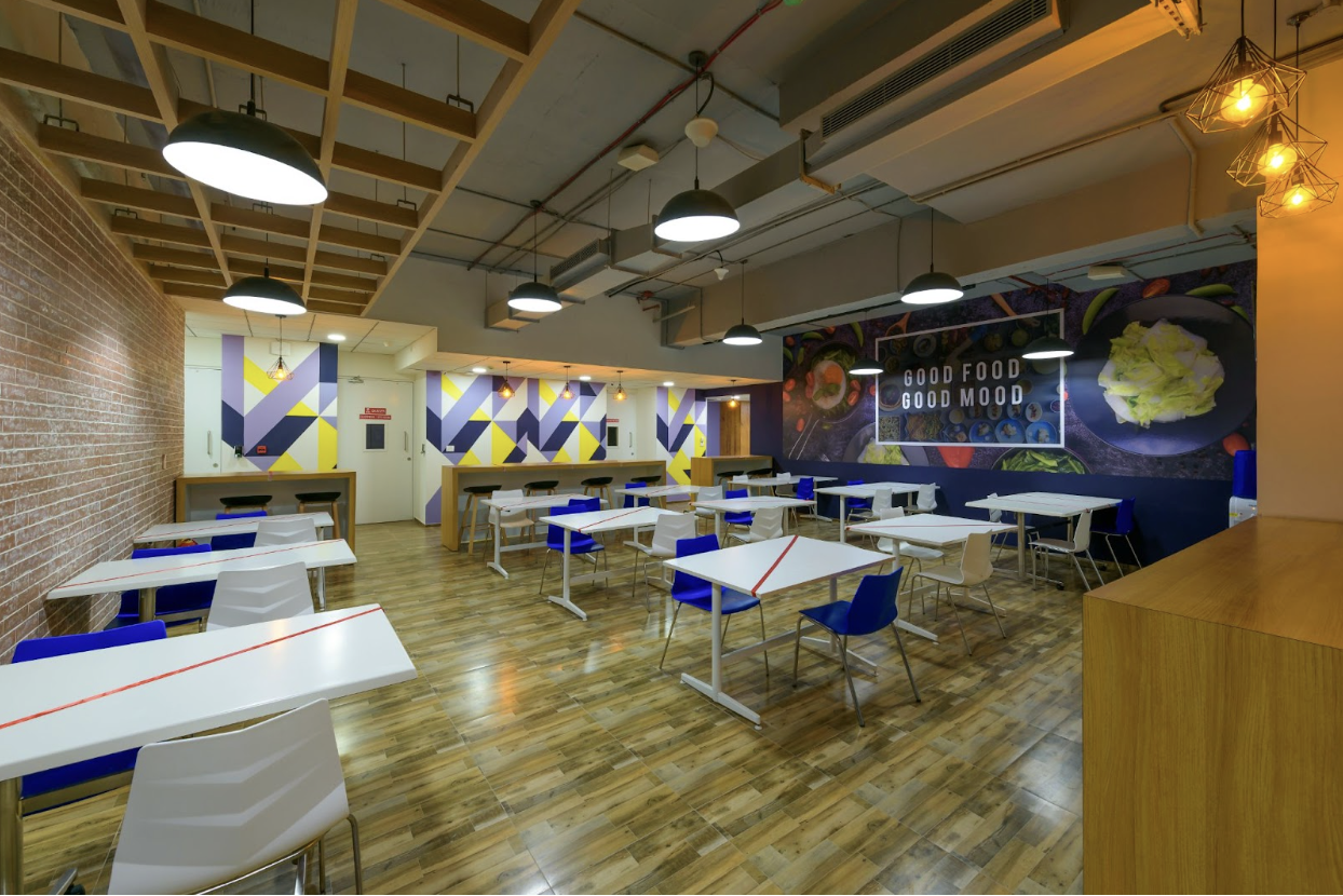 Modern cafeteria space in a managed office with wooden tables and artistic décor.